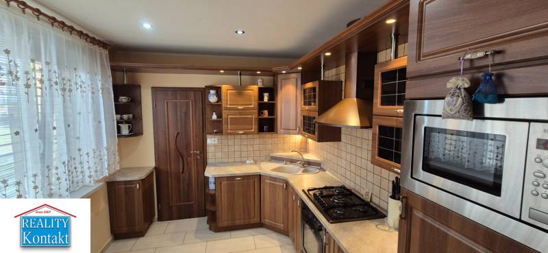 A kitchen of a one-room apartment with a wooden cabinet and built-in appliances.