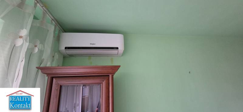 Air conditioning placed above the cabinet and a green wall in a studio apartment.