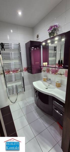 A bathroom in a studio apartment with dark furniture, decorations, and elegant sanitary ware.