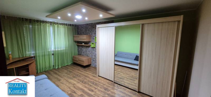 Living room with wooden floor, green curtains, and a large built-in wardrobe.