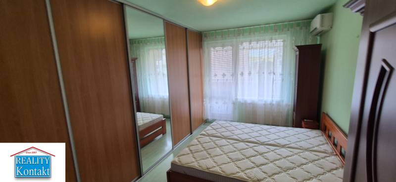 A bedroom in a one-room apartment with a sliding mirror wardrobe and a double bed.