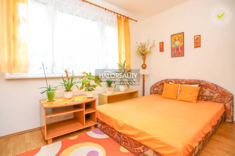 A bright bedroom with an orange bed and houseplants in a 3-room apartment.