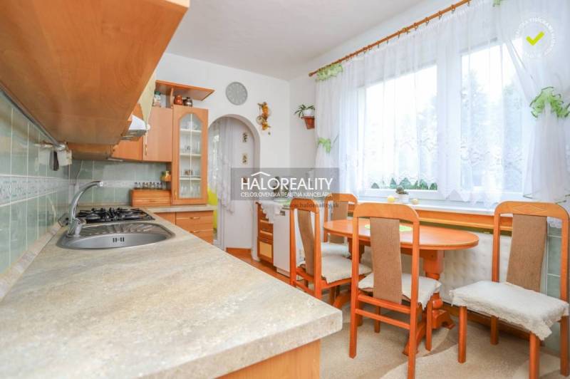 A kitchen in a 3-room apartment with a table and chairs, wooden cabinets, a window with curtains.