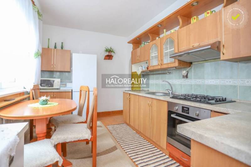A kitchen in a 3-room apartment with wooden furniture and a dining table with three chairs.