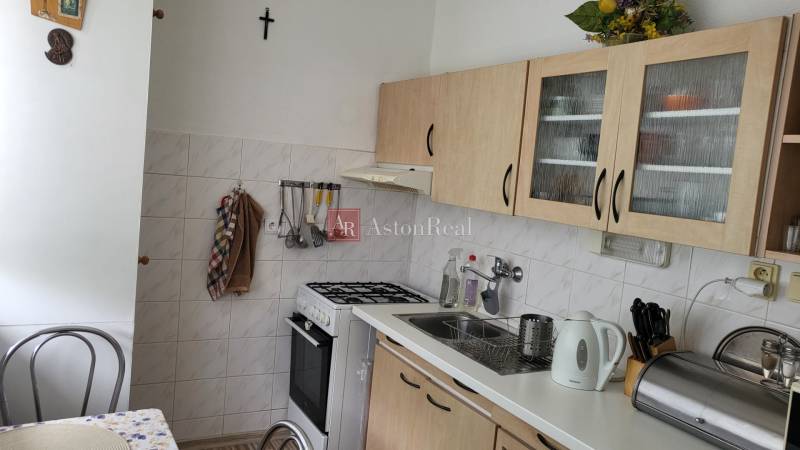 A kitchen in a 3-room apartment with a stove, glass cabinets, and a double sink.