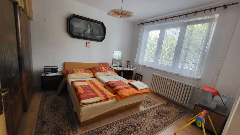 Bedroom in a 3-room apartment with a window, bed, and carpets on the floor.