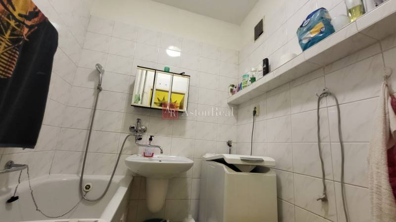 Bathroom with a bathtub, sink, and washing machine in a 3-room apartment.