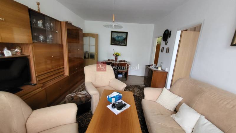 Living room in a 3-room apartment with comfortable seating and wooden cabinets.