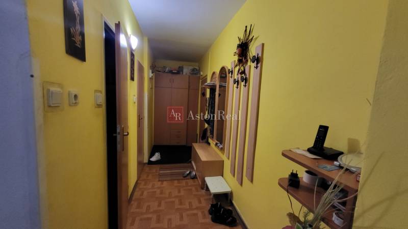 A hallway in a 3-room apartment with yellow walls, wardrobes, and a wall-mounted coat rack.