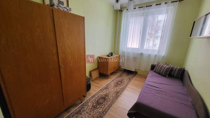 A room in a 3-room apartment with simple furniture, a sofa, and a carpet.