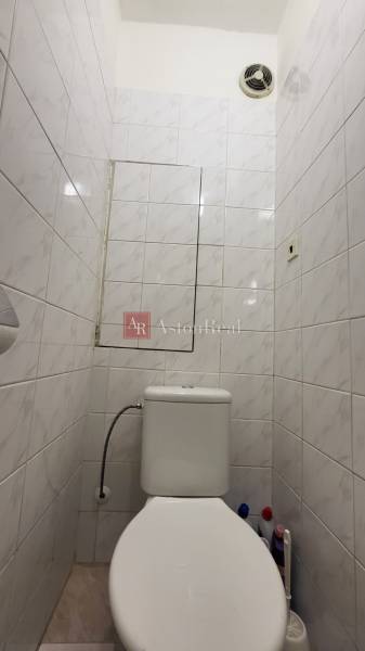A bathroom with tiles in a 3-room apartment, a fan on the ceiling.