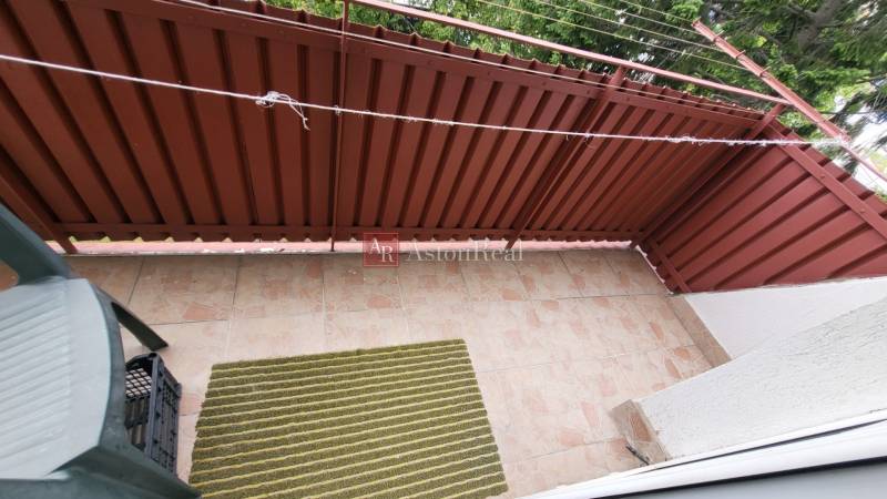 A balcony with tiles and brown railing in a 3-room apartment.