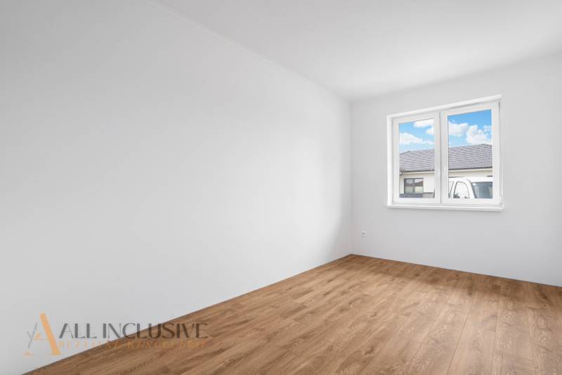 A room in a family house with a wooden floor and a window on the wall.