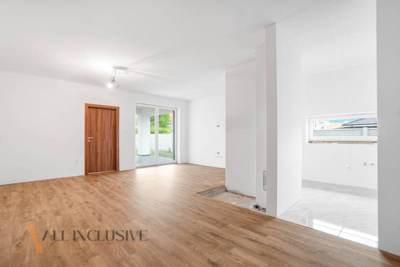 Interior of a family house with light walls, wooden floor, and sliding doors to the terrace.