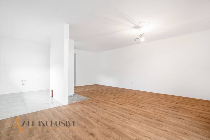 A spacious room with wooden flooring in a family house and white walls.