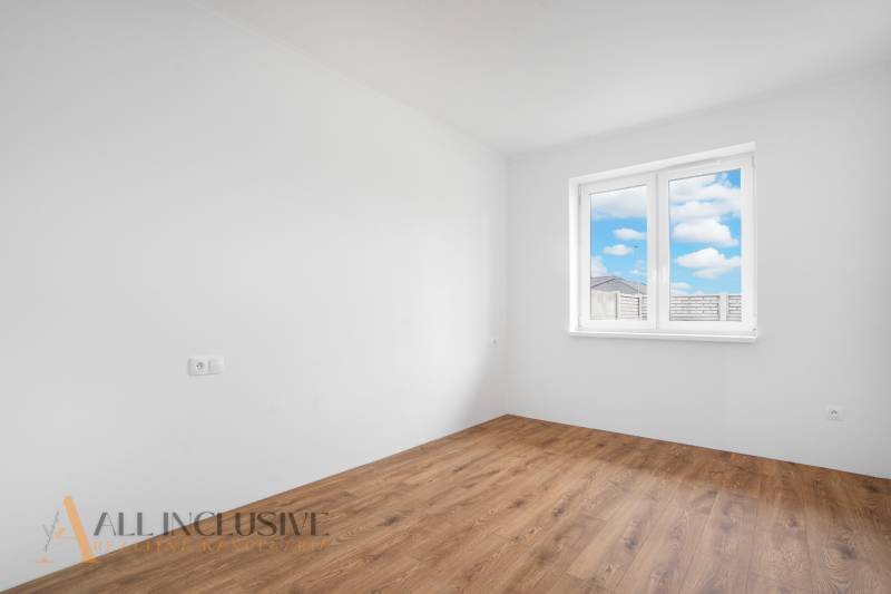 An empty room with a wooden floor in a family house, large window with a view.