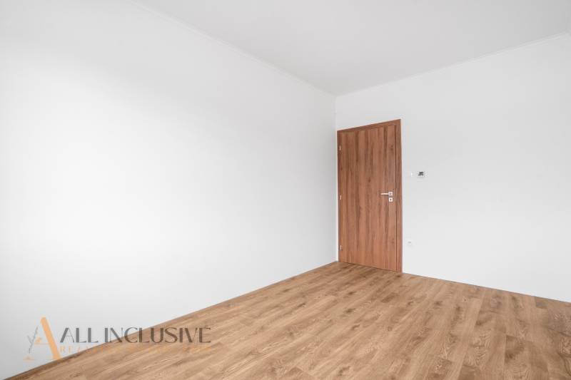 An empty room in a family house with white walls and wooden-colored doors.