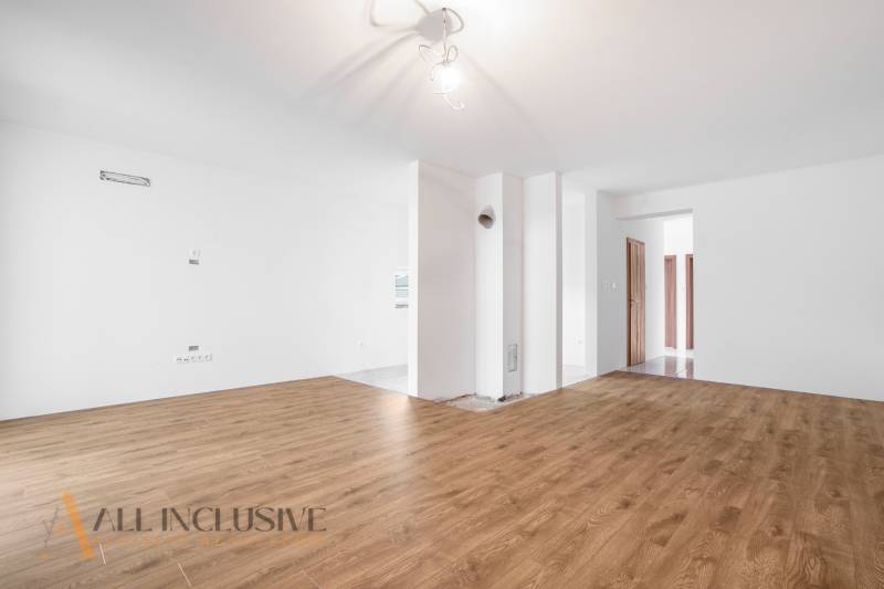 Interior of a family house with wooden flooring, white walls, and an entrance to another room.