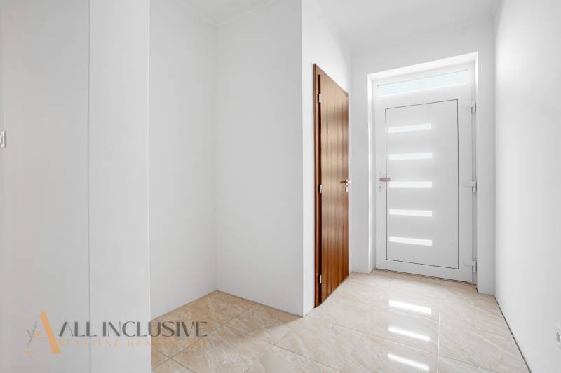 Entrance hall with white walls and wooden doors in a family house.