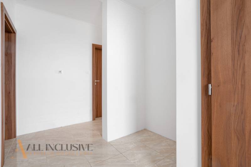 A hallway in a family house with white walls and wooden doors.