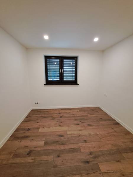 A room in a family house with a wooden floor and a dark window.