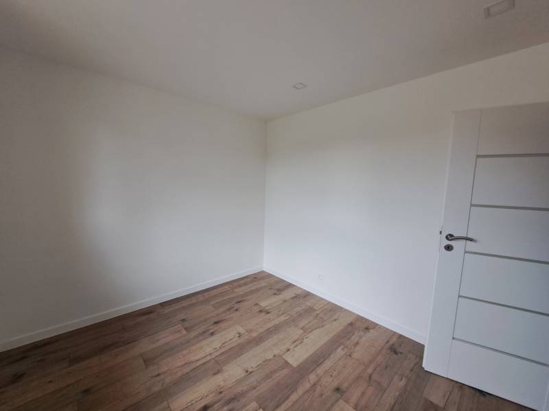 A white empty room in a family house with wooden flooring and white doors.