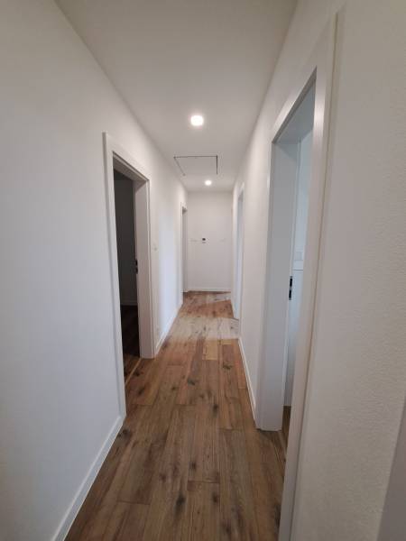 A hallway in a family house with a wooden floor and three rooms.