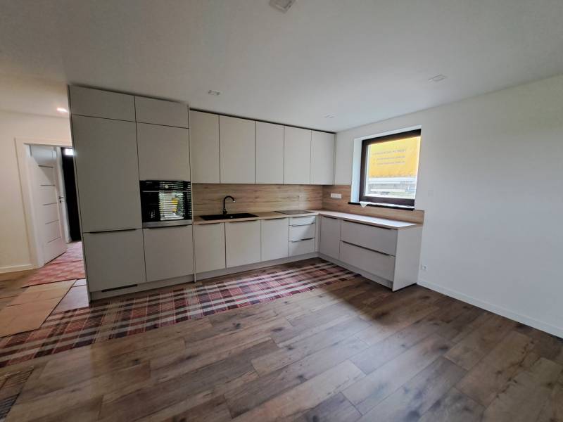 A kitchen in a family house with built-in cabinets and a beautiful wooden floor.