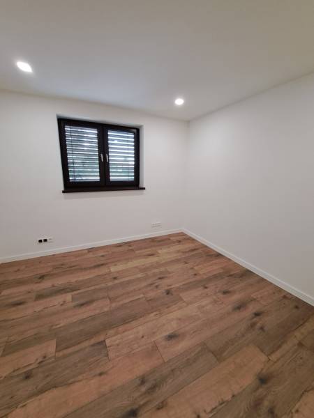 An empty room with a wooden floor and a window in a family house.