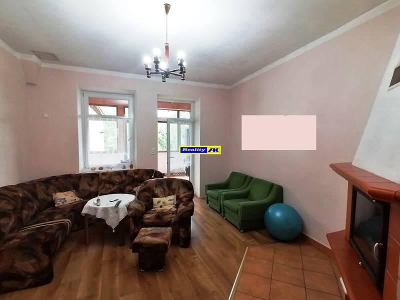 Living room in a family house with a leather sofa, armchairs, and a wood-burning fireplace.