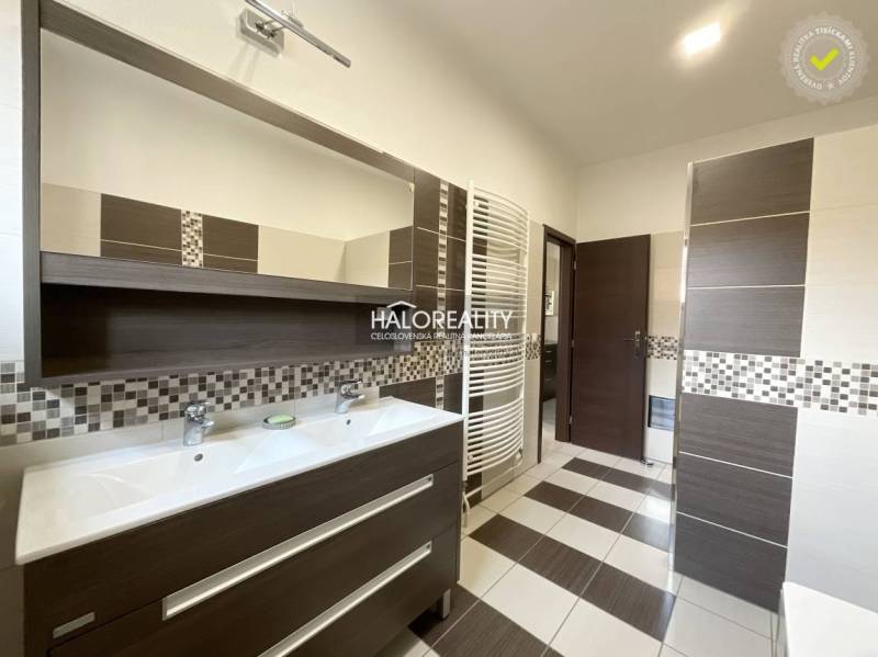 A bathroom in a family house with a double sink and mosaic tiles.