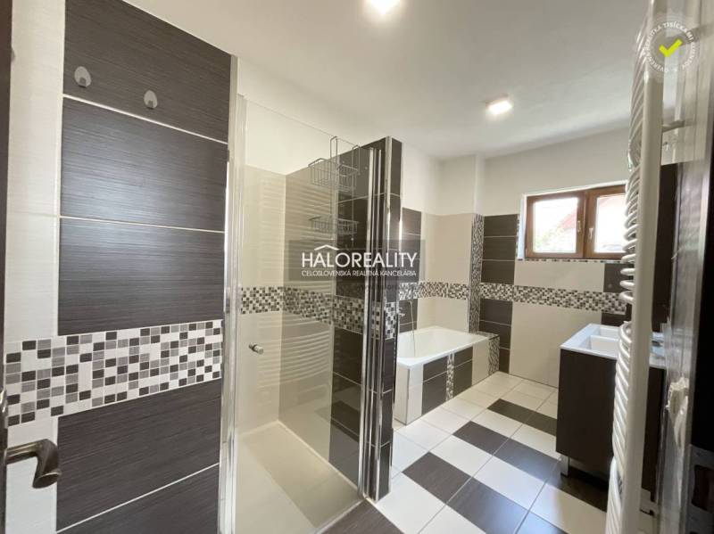 A bathroom in a family house with a bathtub, shower, and sink, decorated with mosaic.