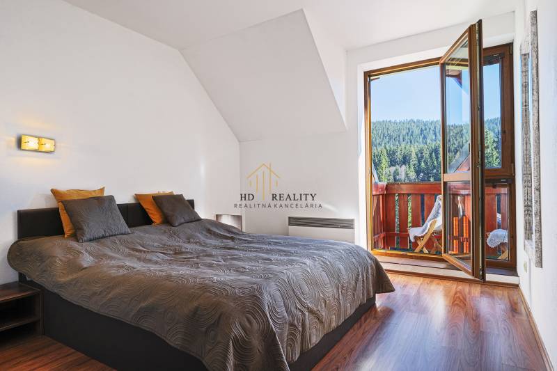 Bedroom with a bed and a balcony in a 2-room apartment with a forest view.