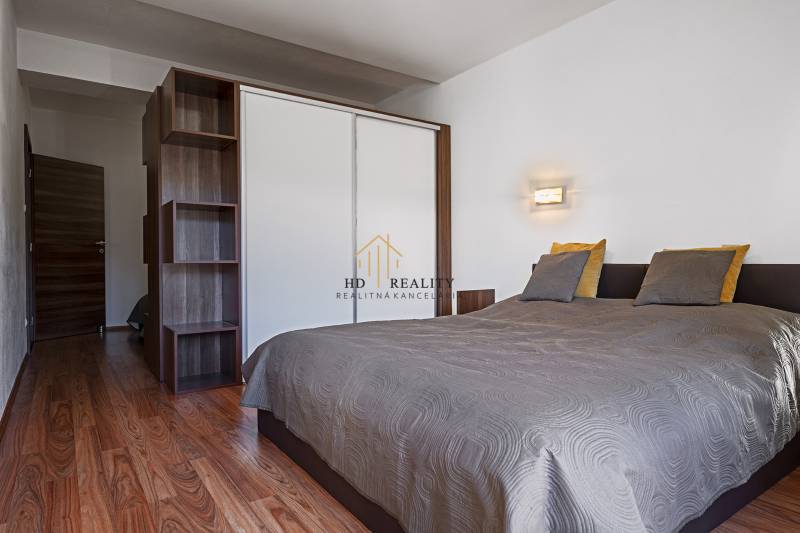 Bedroom with a double bed, wardrobe, and wooden floor in a 2-room apartment.