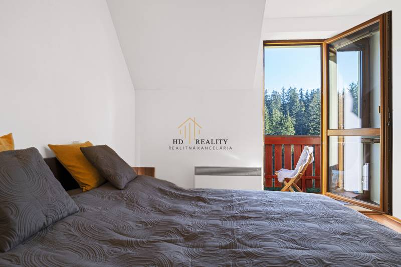 Bedroom of a 2-room apartment with a view of the forests through an open balcony.