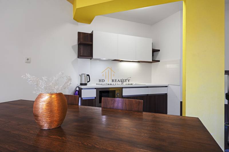 A kitchen in a 2-room apartment with yellow walls, a table, and a vase.