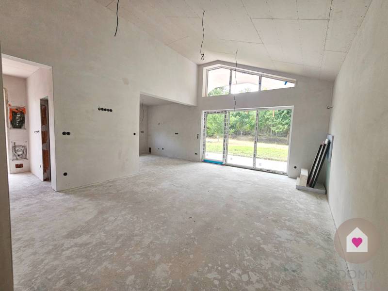 A spacious unfinished room in a family house with large windows and a view of the garden.