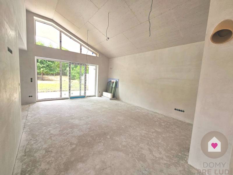 A spacious living room of a family house with large glazing and a view of the garden.