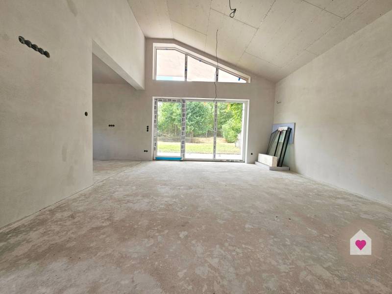 A large, unfurnished space in a family house with a window to the garden.