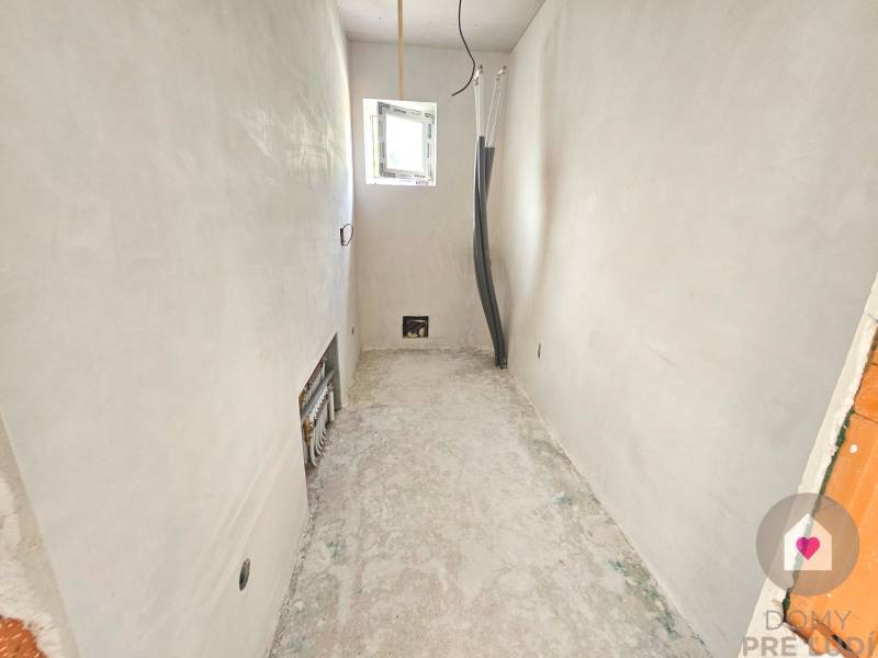 Empty room with white walls and exposed piping in a family house.
