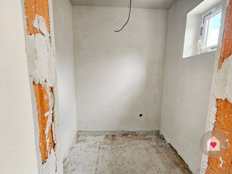 The space in the family house shows raw walls and a small window without flooring.