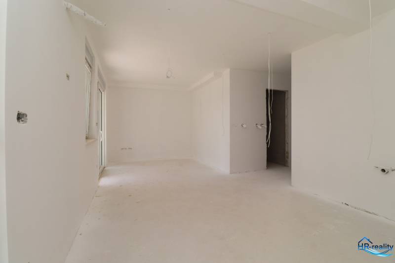 An empty space in a recreational apartment with white walls and cables on the ceiling.