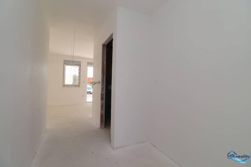A hallway with light walls leading to a room in a vacation apartment.