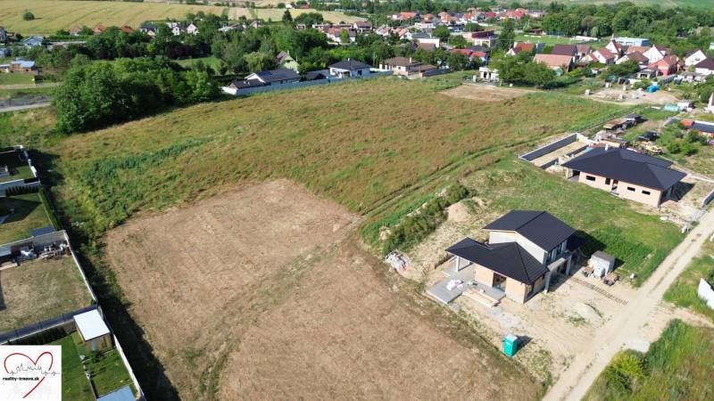 Construction of houses on Krátka Street in Alekšince with unfinished buildings and surrounding nature.