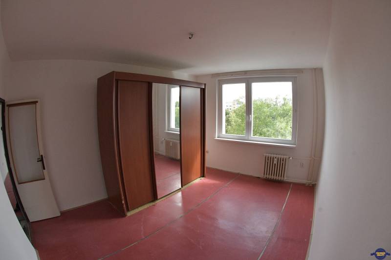 A room with large windows and a wardrobe in a 2-room apartment.