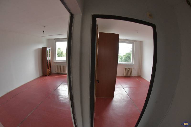 Two empty rooms with red flooring and radiators in a two-room apartment.