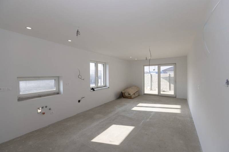 A room under construction in a family house with prepared installations and a concrete floor.