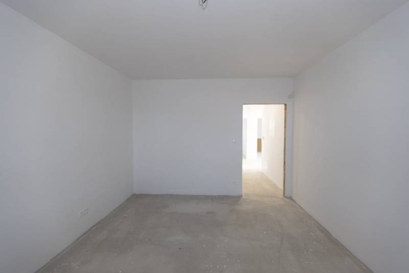 An empty room with a concrete floor and white walls in a family house.