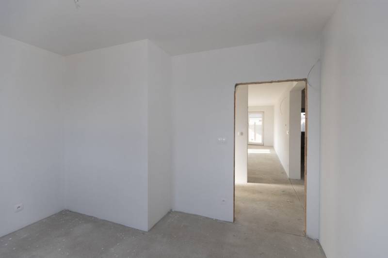 Empty room in a family house with a concrete floor and white walls.