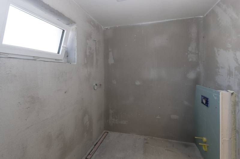 A concrete room under construction in a family house, with a small window and installation.